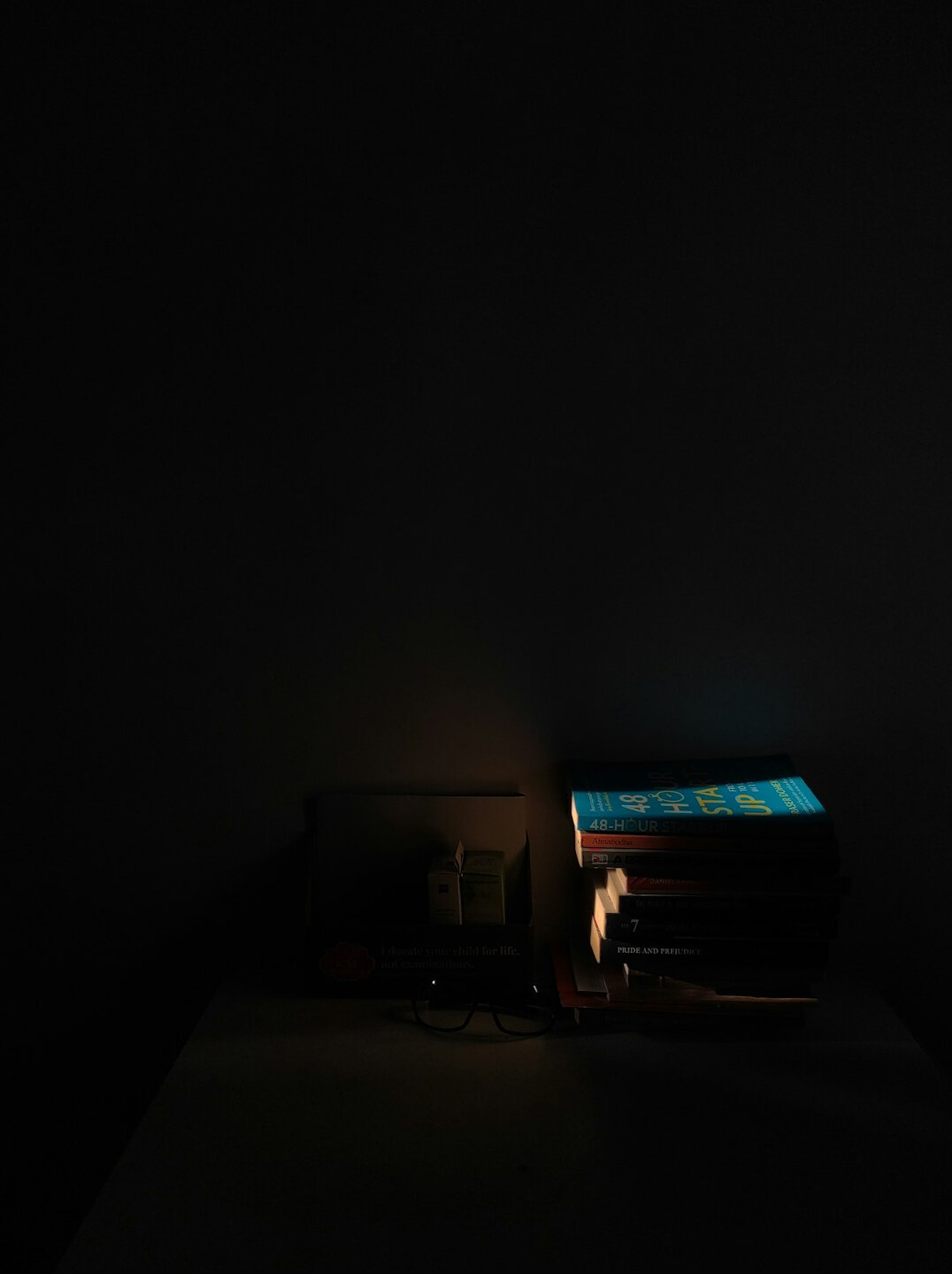 Dark study desk with lamp, stacked books and a typewriter