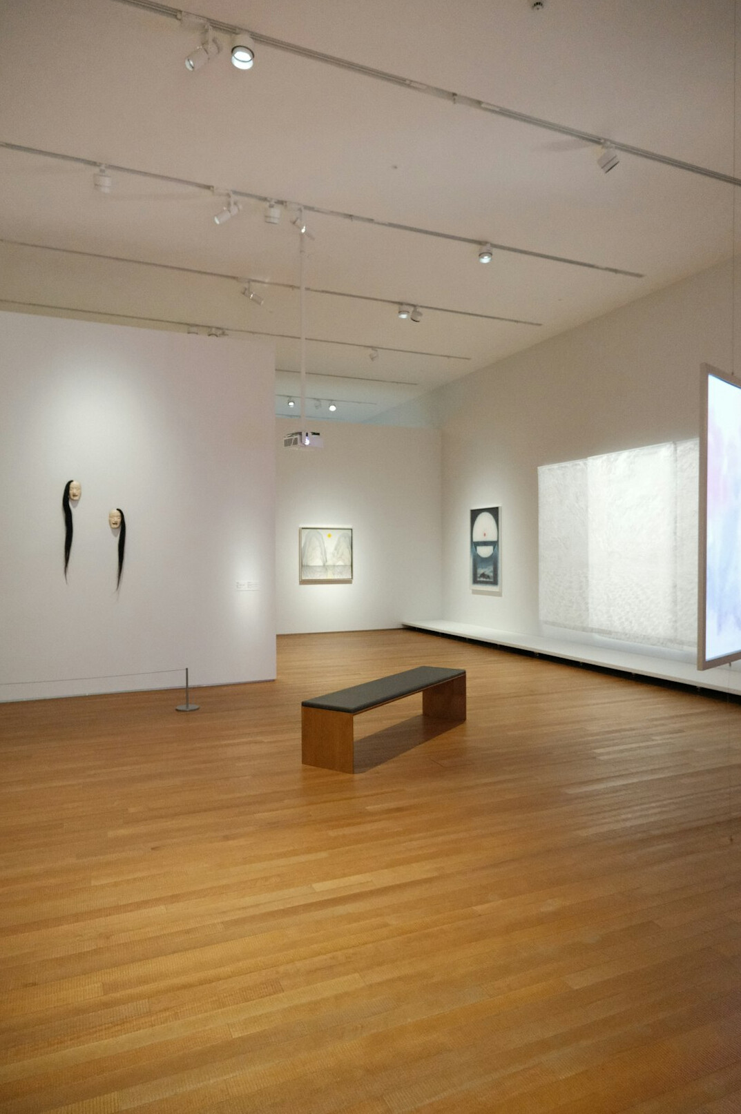 Quiet museum gallery with pale walls and a single bench